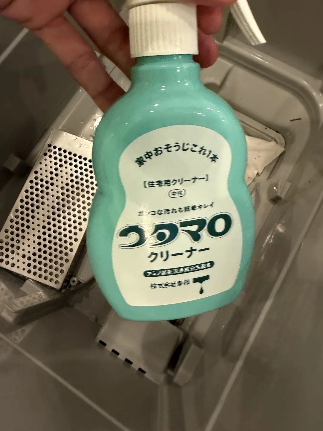 食洗機の庫内でウタマロクリーナー（住宅用・中性）のボトルを手に持っている